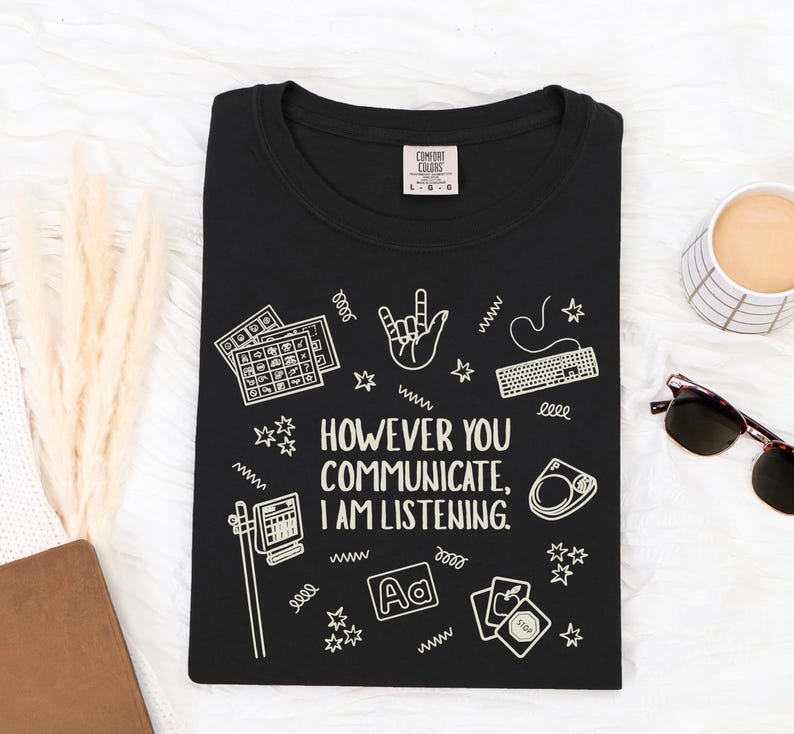 May include: Black t-shirt with the text "HOWEVER YOU COMMUNICATE, I AM LISTENING." and various white graphic icons. The shirt has a crew neck and a Comfort Colors tag.