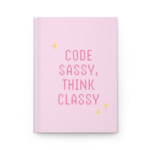 May include: Pink notebook with the text "CODE SASSY, THINK CLASSY" in pink pixelated font and gold stars on a pink background.