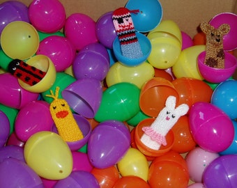 May include: A collection of colorful plastic Easter eggs with various knitted finger puppets inside. The puppets include a ladybug, a chick, a bunny, a pirate, and a dog.