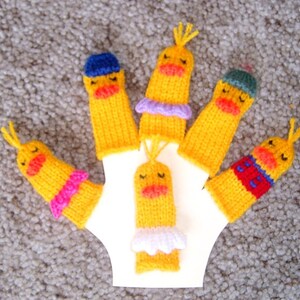 May include: Five yellow finger puppets with different colored accents. Each puppet has a different facial expression and a knitted design. The puppets are on a white background.