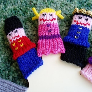 May include: Five knitted finger puppets, each with a different design and color. The puppets include a girl with yellow hair and a pink dress, a boy with a blue and black outfit, a girl with a purple and pink dress, a boy with a blue and black outfit, and a girl with a purple and pink dress.