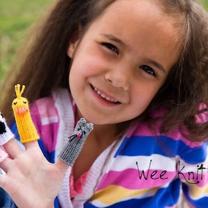 May include: A young girl wearing a pink and blue striped shirt with the text "Wee Knit" is wearing finger puppets on her fingers. The finger puppets are a cow, a chick, a pig, and a cat.
