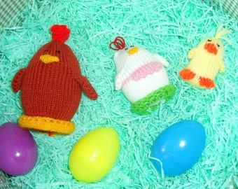 May include: A brown knitted chicken, a white knitted chicken, a yellow knitted chick, and three plastic Easter eggs in a green shredded paper basket.