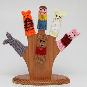 May include: A wooden hand puppet stand with six finger puppets. The puppets are made of knitted yarn and feature various characters, including a bear, a pig, a tiger, a rabbit, and two human figures.