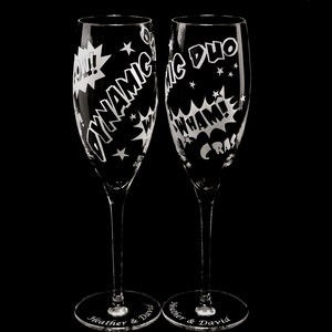 Two clear glass champagne flutes with etched comic book style designs. One flute says "Dynamic Duo" and the other says "CRASH WHAM!" with a "POW!" graphic.  names and wedding date engraved on the flute bases.