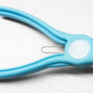 May include: A light blue jewelry pliers tool with a white center and pointed tips. The pliers have curved handles and a silver metal spring. The tool is designed for precision work in jewelry making and crafts.