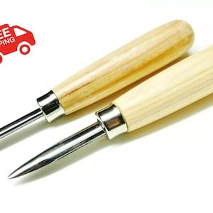 May include: Two wood handled carving tools with metal blades. The tools are lying on a white surface.