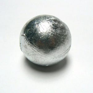 May include: A silver-coloured metal sphere with a smooth, slightly textured surface.