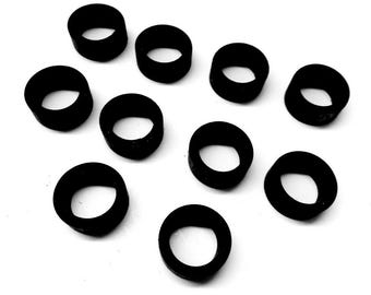 May include: Ten black rubber rings, all the same size, are scattered on a white surface.