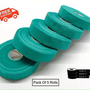May include: Five rolls of teal athletic tape are stacked diagonally, showcasing the product. The text "Pack of 5 Rolls" is visible. Instructions on how to use the tape are also included. The image also includes a red truck with the words "FREE SHIPPING".