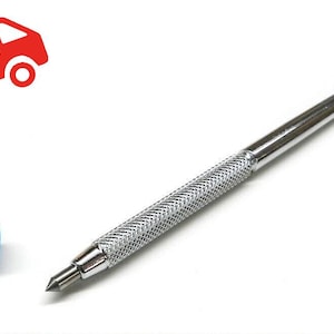 May include: A silver-colored glass cutter with a textured handle and a blue protective cap. The tool has a sharp, pointed tip for precise cutting. The image also includes a red truck with the words "FREE SHIPPING".