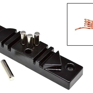 May include: A black jewellery-making tool with silver posts and a separate silver cylinder. A small inset shows a copper coil. This tool is designed for shaping and forming wire into various jewellery components.