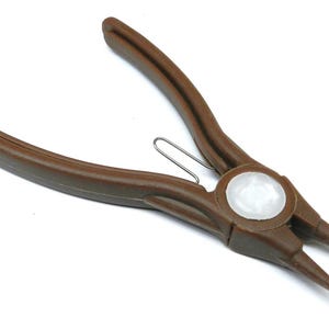 Peut inclure: Pince à circlips marron avec un centre blanc et des pointes. L'outil est doté d'un ressort et est conçu pour saisir et manipuler de petits anneaux ou fixations. La pince est en matériau durable.