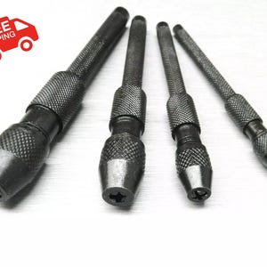 May include: Four black metal drill chucks with a star-shaped opening at the end. The chucks are of different sizes and have a knurled surface.