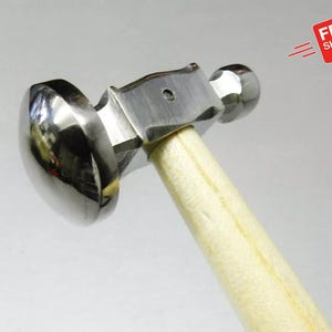 May include: A silver metal hammer with a white wooden handle. The hammer has a rounded head and a smaller round head on the opposite end.