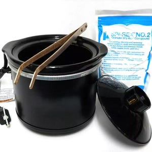 Puede incluir: Olla eléctrica negra para fundir cera con tapa y pinzas de metal. La olla está enchufada a una toma de corriente. Una bolsa de Sparex No. 2 Granular Dry Acid Compound está en el fondo.