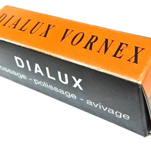 Puede incluir: Caja naranja y negra con el texto "Dialux Vornex" y "Dialux brossage - polissage - avivage" impreso en ella.