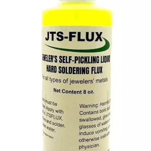 Könnte beinhalten: Eine gelbe Flasche JTS-FLUX, selbstätzender flüssiger Hartlötflussmittel, für alle Arten von Juweliermetallen. Die Flasche ist mit Anweisungen und einer Warnung über den Inhalt gekennzeichnet. Nettoinhalt: 237 ml.