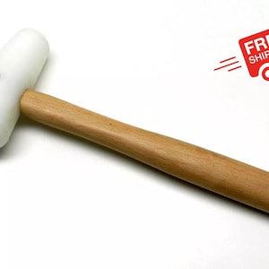 May include: A white rubber mallet with a wooden handle. The mallet has a rounded head and a screw in the center.