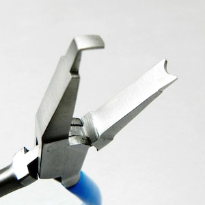 May include: Close-up of a metal jewelry pliers with blue handles. The pliers are open, showcasing the angled jaws designed for shaping and manipulating wire or small components. The tool is against a white background.