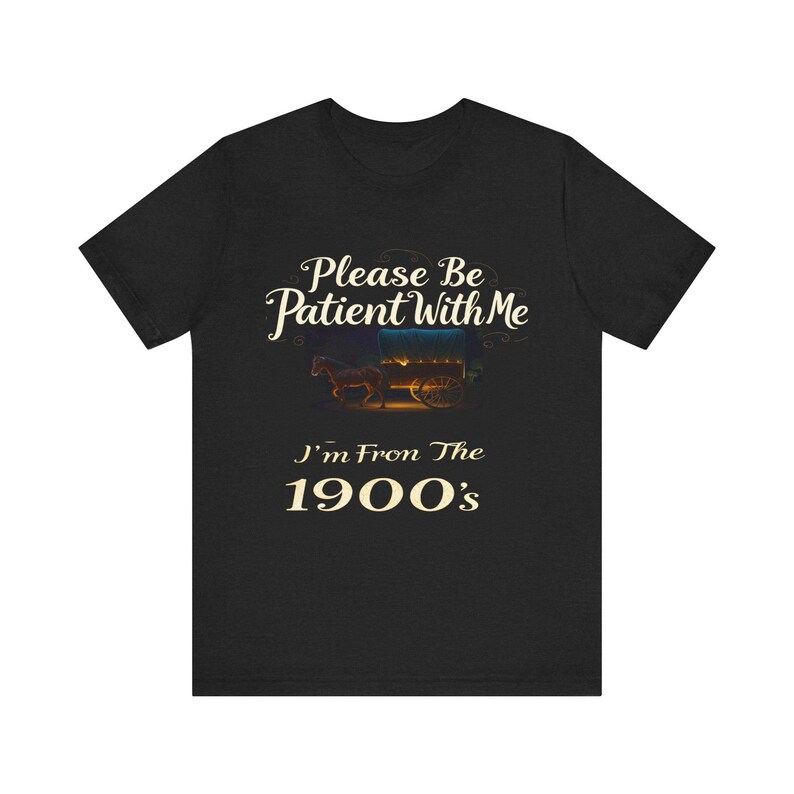 May include: Dark heather gray t-shirt featuring a vintage-style design. The text reads, 'Please Be Patient With Me I'm From The 1900's.'  A small image of a horse-drawn wagon is displayed above the text. The shirt is a comfortable, casual style, suitable for everyday wear.