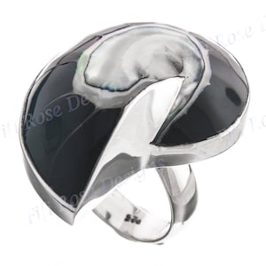 May include: A silver ring with a black and white abalone shell inlay. The ring is shaped like a crescent moon and has a smooth, polished finish.