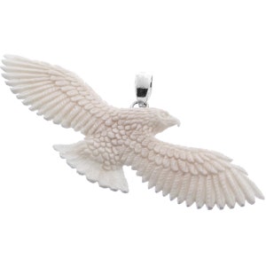 Puede incluir: Un colgante de águila de hueso blanco con tallado detallado. El colgante tiene una argolla de plata.