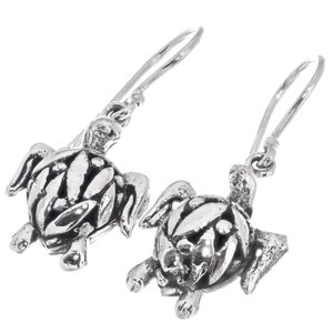 May include: Sterling silver turtle dangle earrings. The turtles are detailed with a textured shell and have a dangling hook closure.