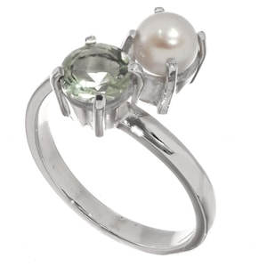 Op de afbeelding: Een zilveren ring met een groene edelsteen en een witte parel. De ring is ontworpen met de parel en de edelsteen aan tegenovergestelde zijden van de band.