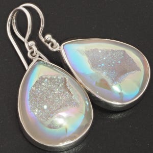 May include: A pair of silver teardrop earrings with iridescent white agate stones. The stones have a sparkly, crystalline texture.