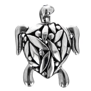 May include: A silver-toned turtle pendant with a detailed leaf and dot pattern on its shell. The pendant has a three-dimensional design with visible legs, head, and flipper-like appendages. The metal has a polished, reflective surface.