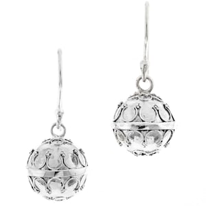 May include: A pair of silver dangle earrings with a round, textured ball charm. The ball has a detailed design of small circles and curves.