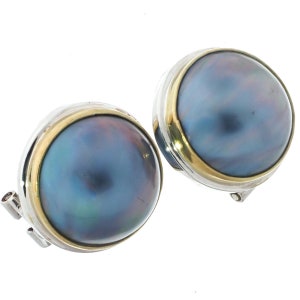 May include: A pair of silver and gold tone clip-on earrings featuring a large, round, iridescent black pearl.