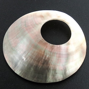 May include: A large, iridescent, mother-of-pearl shell with a round hole in the center. The shell has a light gray, green, and pink color.
