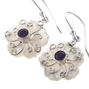 May include: A pair of silver earrings with a white flower design and a purple amethyst gemstone in the center of each flower.