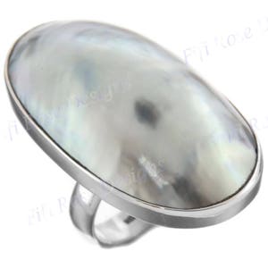 May include: A silver ring featuring a large oval-shaped mother-of-pearl stone. The stone is light grey with a subtle iridescent sheen.