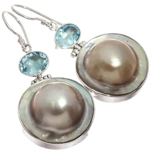 May include: Silver drop earrings featuring large, lustrous gray pearls set in a silver bezel. Each earring has a light blue gemstone above the pearl. The earrings have a hook closure.