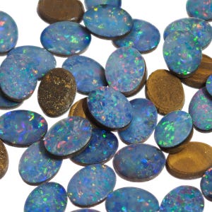 May include: A collection of oval-shaped opal gemstones, each with a unique iridescent blue and green color pattern. The opals are set in a brown backing material.