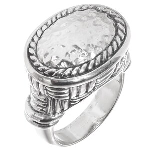 May include: A silver ring with an oval, hammered-texture face framed by a rope-like border. The ring's band features a woven design, adding texture and detail. The ring is a statement piece, suitable for everyday wear or special occasions.