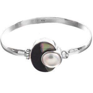 Può includere: Un braccialetto rigido in argento con una conchiglia nera e iridescente e un accento di perla bianca. Il braccialetto è contrassegnato "925" all'interno.