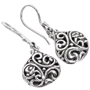 May include: Silver filigree dangle earrings with a teardrop shape. The earrings have a delicate, intricate design with swirls and loops.