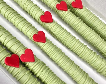 May include: Five green chocolate-covered pretzel rods with red heart-shaped decorations.