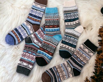 May include: Five pairs of colorful patterned socks with a white background. The socks have a geometric design with blue, brown, and red accents.