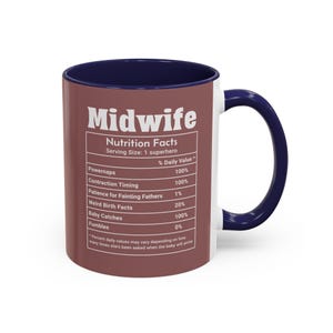 May include: A white ceramic mug with a navy blue handle and interior. The mug features the word "Midwife" in large white letters, along with a "Nutrition Facts" label listing daily values for various midwife skills. The mug has a brown exterior.