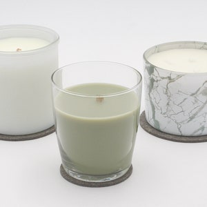 May include: Three candles in glass jars with felt coasters. The candles are white, green, and white with a marble pattern.