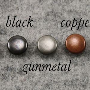 May include: Five round metal rivets in silver, black, gunmetal, copper, and brass finishes. Each rivet is labelled with its colour name in a cursive font. Ideal for leathercraft or garment making.