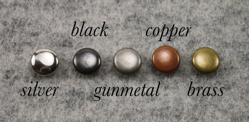 May include: Five round metal rivets in silver, black, gunmetal, copper, and brass finishes. Each rivet is labelled with its colour name in a cursive font. Ideal for leathercraft or garment making.