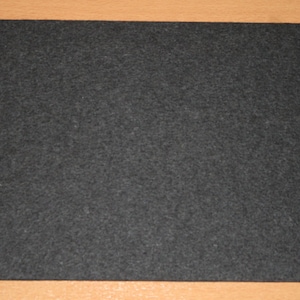 May include: A black felt mouse pad. The pad is rectangular and has a smooth surface.