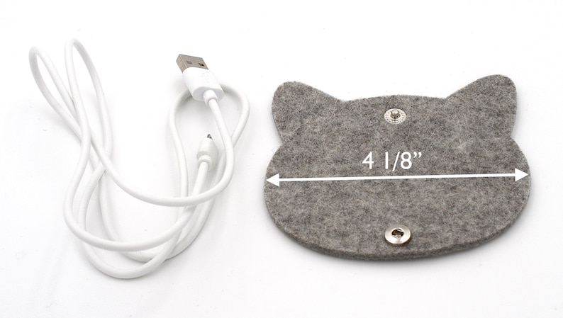 May include: A grey felt cat-shaped cord organiser with two silver snaps and a white USB charging cable. The organiser measures 10.5 cm wide.