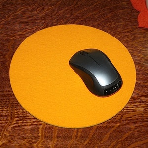 May include: A round orange mouse pad with a black wireless mouse on top.